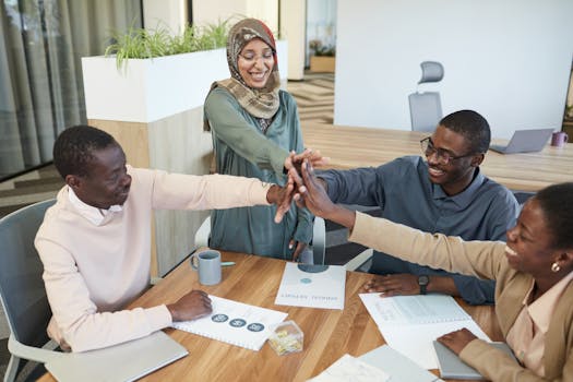 A diverse group of colleagues collaborating and celebrating success in a modern office setting.