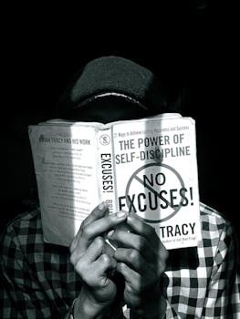 Black and white photo of a person reading a book on self-discipline, highlighting focus and learning.